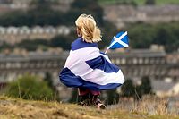 ARCHIV - 21.09.2013, Großbritannien, Edinburgh: Ein Kind, in eine schottische Flagge gehüllt, geht während einer Demonstration für die schottische Unabhängigkeit über einen Rasen. (zu dpa "Bye, bye, London - Wieso junge Schotten unabhängig sein wollen") Foto: Graham Stuart/epa/dpa +++ dpa-Bildfunk +++