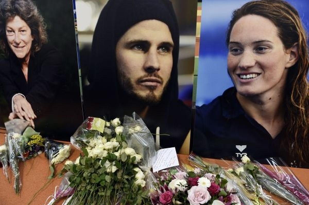 TOPSHOTS Flowers have been put in front of pictures on March 11, 2015 at the Insep (French Sport Academy in Vincennes, outside Paris, during a ceremony in memory of Olympic champion swimmer Camille Muffat (R), yachtswoman Florence Arthaud (L) and Olympic boxer Alexis Vastine (C) who died two day earlier with five French TV crew members and two Argentine pilots in the crash of helicopters in Argentina. AFP PHOTO / LOIC VENANCE