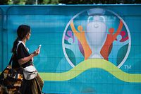 A pedestrian walks past the logo of the UEFA EURO 2020 European Football Championship in Copenhagen, one of the tournament's host cities, on June 10, 2021. (Photo by JONATHAN NACKSTRAND / AFP)