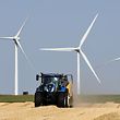 A farmer makes straw bales with his tractor after harvesting, on July 23, 2019, in Guigneville, centre France, in front of wind turbines. (Photo by Jean-Francois MONIER / AFP)