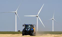 A farmer makes straw bales with his tractor after harvesting, on July 23, 2019, in Guigneville, centre France, in front of wind turbines. (Photo by Jean-Francois MONIER / AFP)