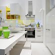 Die weiße Küche wird mit gelben Regalen aufgefrischt, ein weiterer Hingucker sind Becher, Vasen und Kräuter in sattem Grün.

