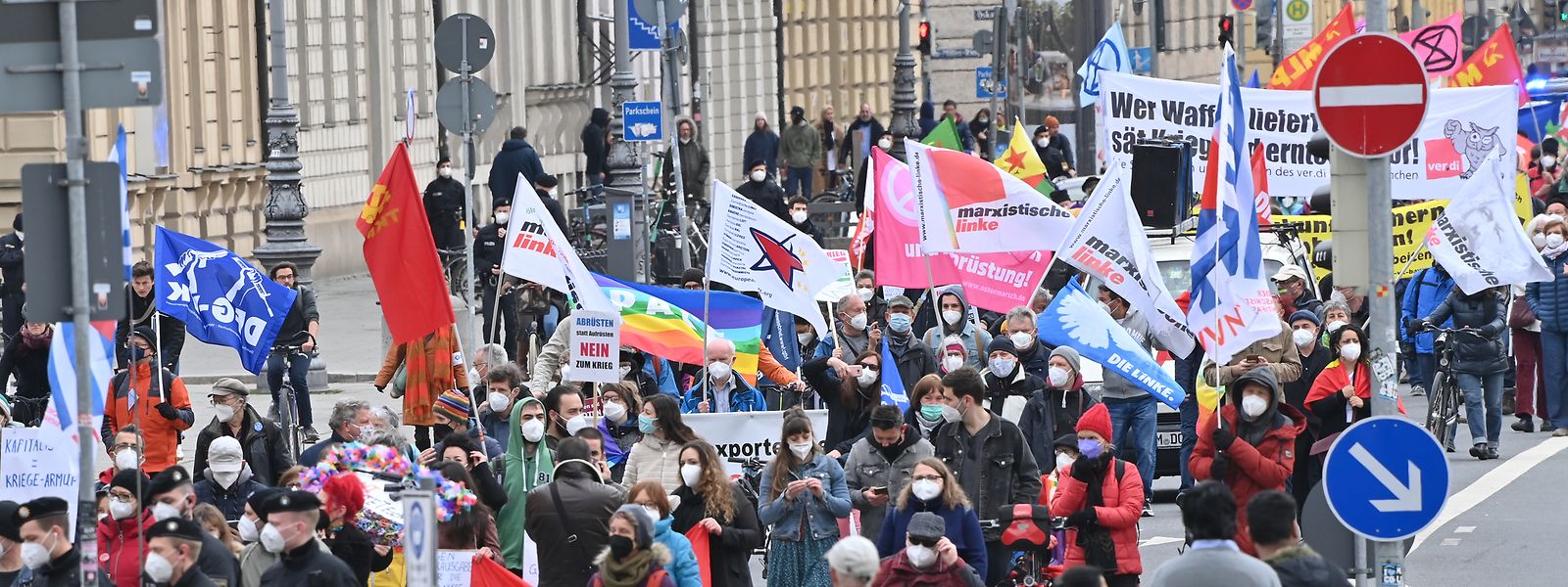 Teilnehmer gehen beim Ostermarsch mit Bannern, Fahnen und Plakaten durch München.