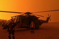 This undated handout photo received on January 5, 2020 from the Australian Department of Defence shows red skies from bushfires hanging over an Army 6 Aviation Regiment MRH-90 at Polo Flat, Cooma, during bushfire relief efforts. - Australians on January 5 counted the cost from a day of catastrophic bushfires that caused "extensive damage" across swathes of the country and took the death toll from the long-running crisis to 24. (Photo by Handout / AUSTRALIAN DEPARTMENT OF DEFENCE / AFP) / RESTRICTED TO EDITORIAL USE - MANDATORY CREDIT "AFP PHOTO / AUSTRALIAN DEPARTMENT OF DEFENCE" - NO MARKETING NO ADVERTISING CAMPAIGNS - DISTRIBUTED AS A SERVICE TO CLIENTS