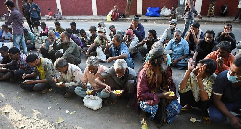 Homeless people eat food offered by volunteers on a street during a government-imposed nationwide lockdown as a preventive measure against the spread of the COVID-19 novel coronavirus in Ahmedabad on March 30, 2020. (Photo by Sam PANTHAKY / AFP)