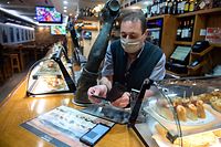 A waiter checks a customer's Covid-19 health pass in a bar of the Spanish Basque city of San Sebastian on December 15, 2021, as it becomes mandatory in the Basque Country in restaurants, bars, sports centres, hospitals, gyms, nursing homes and at indoor cultural events. (Photo by ANDER GILLENEA / AFP)