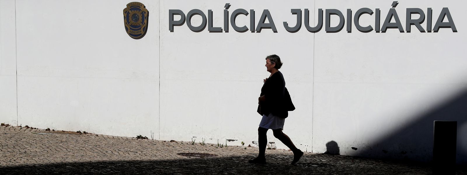 Uma transeunte passa pelo edifício sede da Policia Judiciária em Lisboa, em agosto de 2022. 