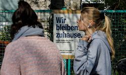 Two woman walk by a restaurant with a sign up which reads "We Stay at Home" in Berlin's Kreuzberg district on March 27, 2020 during the new coronavirus COVID-19 pandemic. (Photo by David GANNON / AFP)
