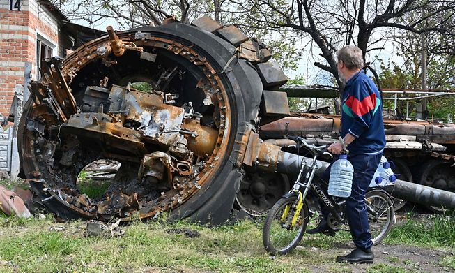 A local resident looks at a destroyed Russian tank next to a residential house in the village of Mala Rogan, east of Kharkiv, on May 15, 2022