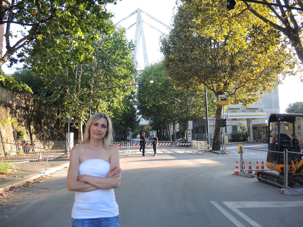 Silvia Varani steht auf der Via Walter Fillak, die seit dem Einsturz der Morandi-Brücke am 14. August gesperrt ist. Sie kann seitdem nicht in ihre Wohnung zurückkehren. Im Hintergrund ist Pylon Nummer zehn zu sehen, der stehengeblieben ist.
