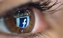 (FILES) In this file photo taken on March 22, 2018 an illustration picture taken in Paris shows a close-up of the Facebook logo in the eye of an AFP staff member posing while she looks at a flipped logo of Facebook. - Ireland's data regulator has launched an official inquiry into Facebook after data on 533 million users was leaked on a hacking website, a spokesman said April 14, 2021. (Photo by Christophe SIMON / AFP)