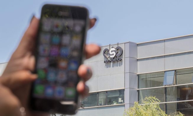 Woman holding a phone in front of NSO Group offices in Israel