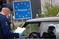 (FILES) In this file photo taken on April 19, 2020 a Belgian Police officer controls the documents of a person in a car at the border between Belgium and France during a police patrol in Quevy, enforcing the social distancing rules, as Belgium is in its fifth week of lockdown to fight the COVID-19 outbreak, caused by the novel coronavirus. - An European coordination for a return to free movement between European countries is delicate, between health imperatives and economic emergency, after the closings of the borders which have damaged a symbol of the European Union. (Photo by BENOIT DOPPAGNE / BELGA / AFP) / Belgium OUT