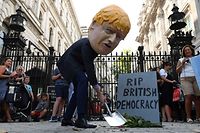 A demonstrator, wearing a mask depicting Britain's Prime Minister Boris Johnson, and a mock gravestone inscribed with the words "RIP British Democracy" protests outside the gates to Downing Street in central London on August 28, 2019. - British Prime Minister Boris Johnson announced Wednesday that the suspension of parliament would be extended until October 14 -- just two weeks before the UK is set to leave the EU -- enraging anti-Brexit MPs. MPs will return to London later than in recent years, giving pro-EU lawmakers less time than expected to thwart Johnson's Brexit plans before Britain is due to leave the European Union on October 31. (Photo by DANIEL LEAL-OLIVAS / AFP)