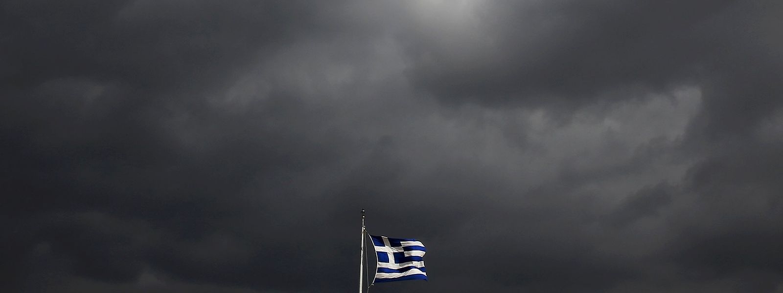 Über der griechischen Flagge ziehen sehr düstere Wolken auf - in manchem Sinne des Wortes.