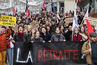Protesters hold flags, placards and a banner reading "the retirement" in a demonstration in Dijon, central-eastern France on March 7, 2023, on the sixth day of nationwide rallies organized since the start of the year against French President's pension reform and its postponement of the legal retirement age from 62 to 64. - Massive strikes are expected from March 7, 2023, with unions promising to bring the country "to a standstill" and strikes set to hit many sectors such as transport, energy and oil refining. (Photo by ARNAUD FINISTRE / AFP)