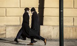 TOPSHOT - A man wearing a face mask walks past a woman with a face mask on March 23, 2020, in Prague, where most activities slowed down or came to a halt due to the spread of the novel coronavirus COVI-19. (Photo by Michal Cizek / AFP)