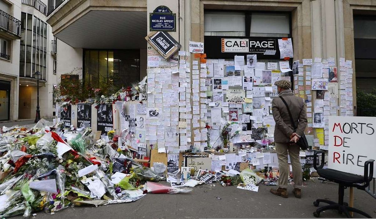 TOPSHOTS People visit a makeshift memorial near the headquarters of the French satirical weekly Charlie Hebdo on January 12, 2015 in Paris in tribute to the 17 victims of a three-day killing spree by homegrown Islamists. France announced an unprecedented deployment of thousands of troops and police to bolster security at "sensitive" sites including Jewish schools today, the day after marches that drew nearly four million people across the country. AFP PHOTO/ BERTRAND GUAY