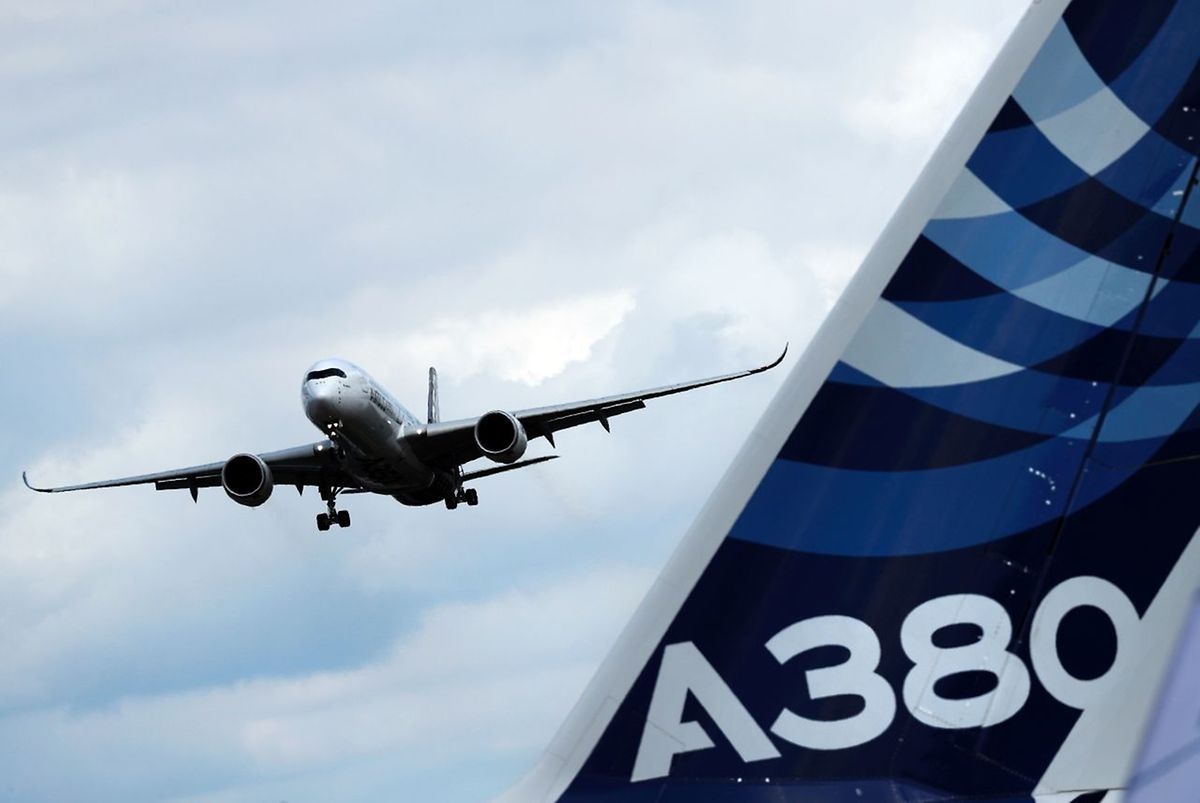 Eine Airbus A350 setzt zum Landeanflug an, im Vordergrund ein Leitwerk des A380-"Jumbos".