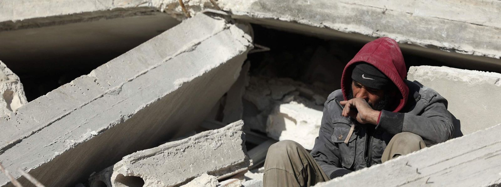 In der Stadt Harim in der syrischen Region Idlib sitzt ein Mann in den Trümmern eines eingestürzten Hauses.
