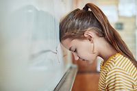 Shot of a young girl leaning against a board in a classroom at school