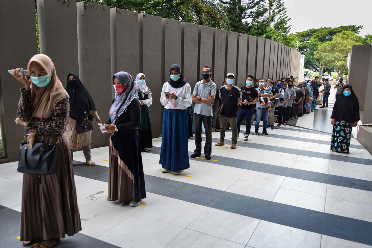 Dezenas de pessoas fazem fila, cumprindo as regras de distanciamento, para entrarem no museu
