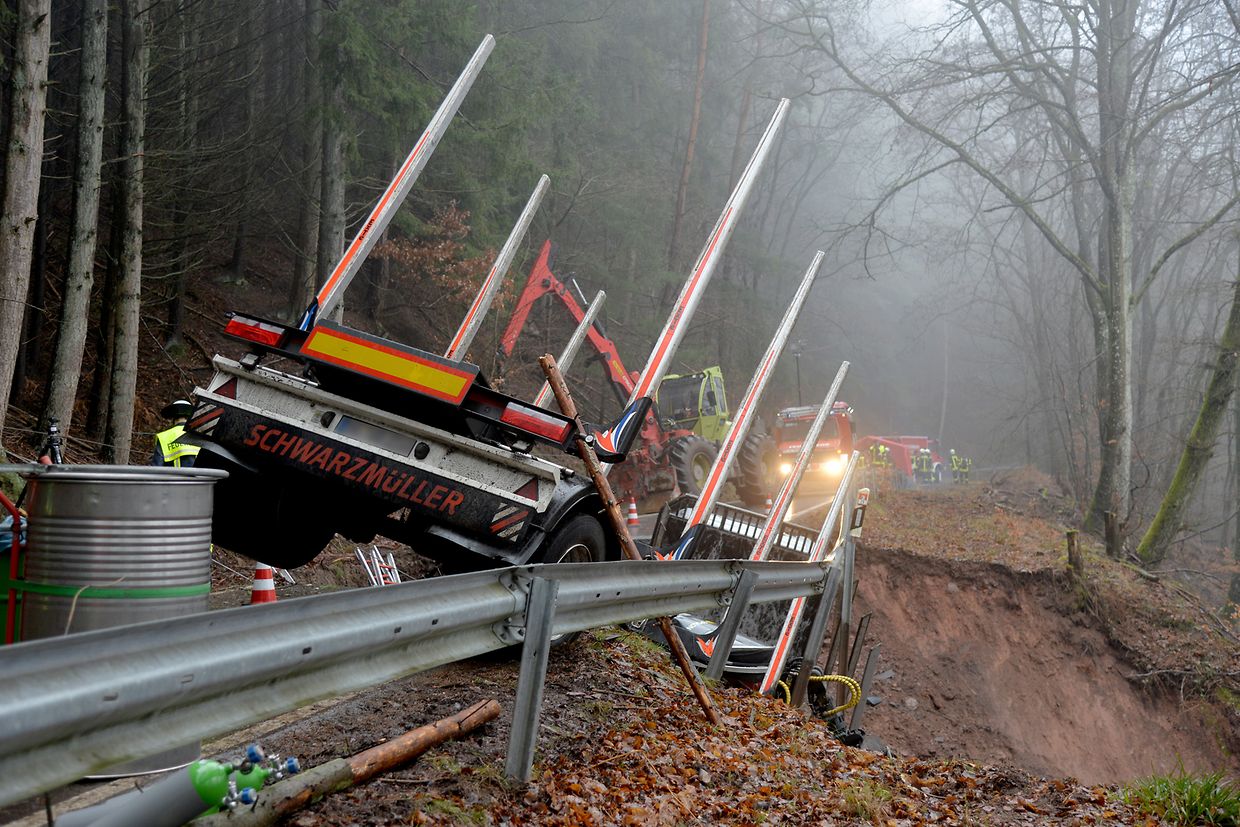 Ein Lastwagen hängt bei Kordel in einem kleinen Krater einer eingebrochenen Straße, in den der Lastwagen und ein Auto beim Befahren der Straße gerutscht waren.