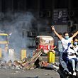An Iraqi protester flashes the victory sign as he rides past the scorched ministry of finance set ablaze by fellow protesters at Baghdad's Khallani square during ongoing anti-government demonstrations on November 11, 2019. - The United States has urged Iraq to hold early polls and carry out electoral reform, after a rights group warned a deadly crackdown on anti-government protesters could spiral into a "bloodbath". Three protesters were shot dead in the southern city of Nasiriyah on November 10 while dozens of demonstrators were wounded in Baghdad. (Photo by SABAH ARAR / AFP)