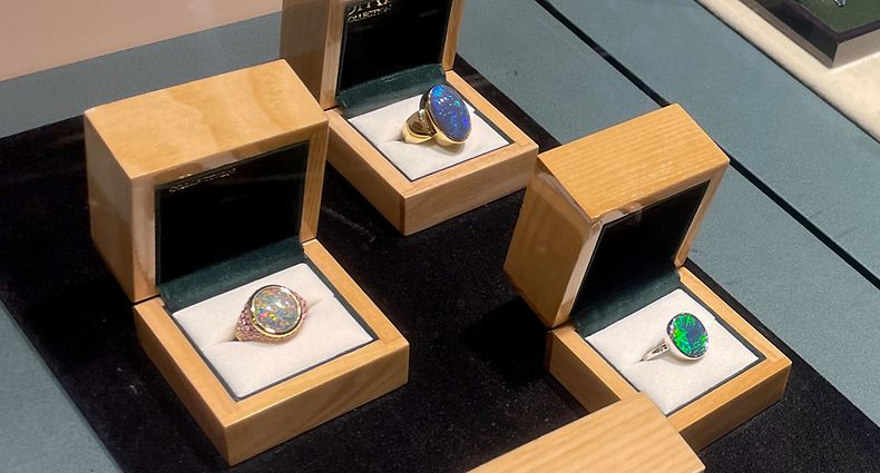 PRODUKTION - 04.05.2023, Australien, Sydney: Mit Opalen verzierte Ringe sind in einer Glasvitrine in der National Opal Collection zu sehen. (zu dpa «Im Rausch der Opale: Australiens faszinierender National-Edelstein») Foto: Michelle Ostwald/dpa +++ dpa-Bildfunk +++