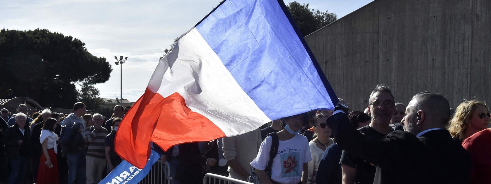 Un homme tient un drapeau national français en attendant d'entrer dans un meeting de campagne de Marine Le Pen (RN) à Perpignan.