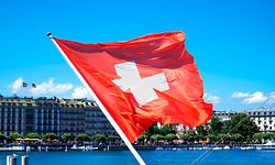 Swiss flag blowing in the wind and the city in the background in Geneva, Switzerland