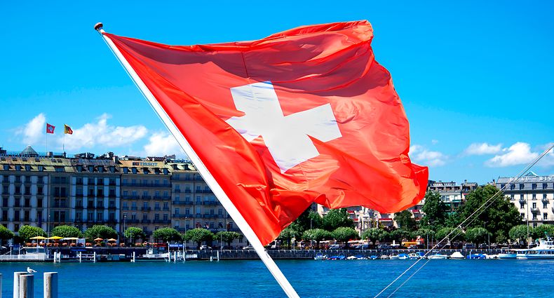 Swiss flag blowing in the wind and the city in the background in Geneva, Switzerland