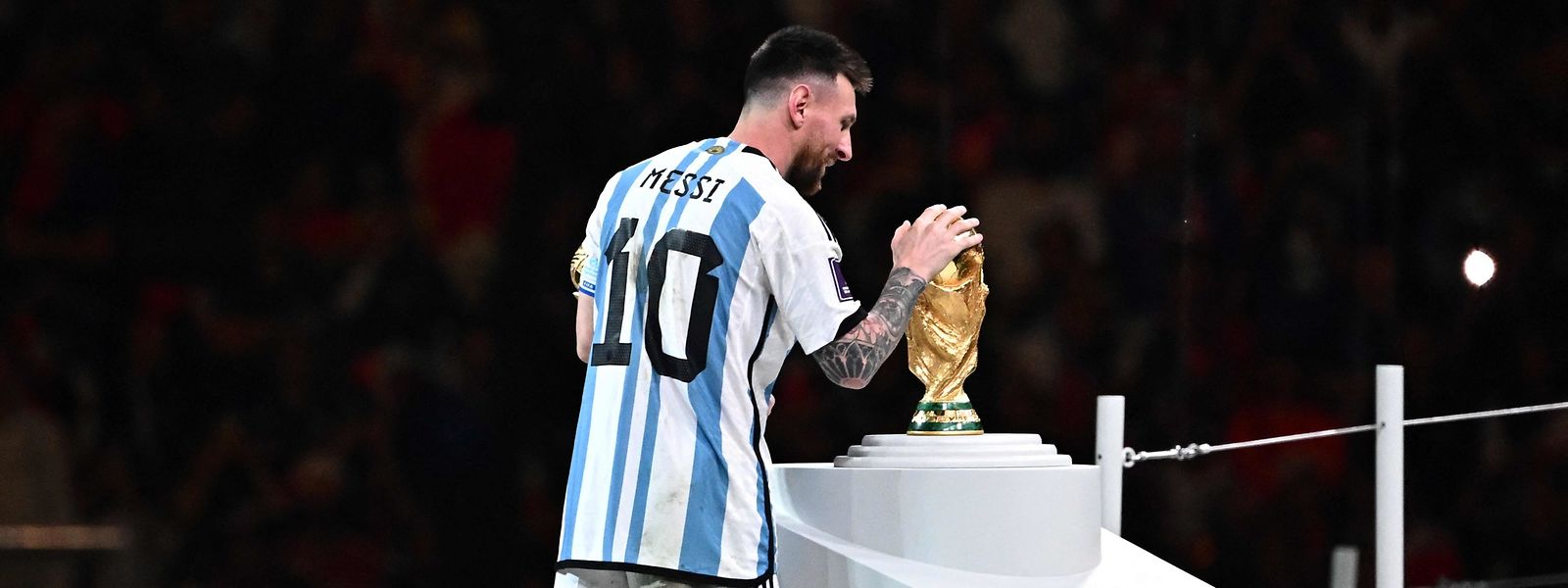 Lionel Messi berührt den WM-Pokal.