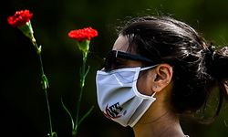 A man wearing a face mask and holding two red carnations takes part in a May Day demonstration respecting the social security distance in Lisbon on May 1, 2020, amid the COVID-19 outbreak caused by the novel coronavirus. - Workers were forced to scale back May Day rallies around the world because of coronavirus lockdowns, although some pushed on with online events and others hit the streets in face masks. (Photo by PATRICIA DE MELO MOREIRA / AFP)