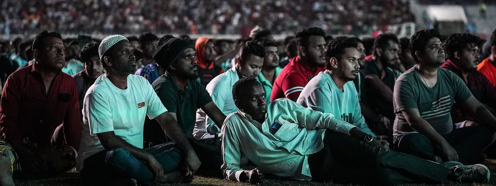 Verkorkste WM, verkorkstes Land: Wanderarbeiter in Katar sehen sich ein WM-Spiel auf einer Großleinwand in einem Stadion im Einkaufskomplex Asian Town am Stadtrand von Doha an.