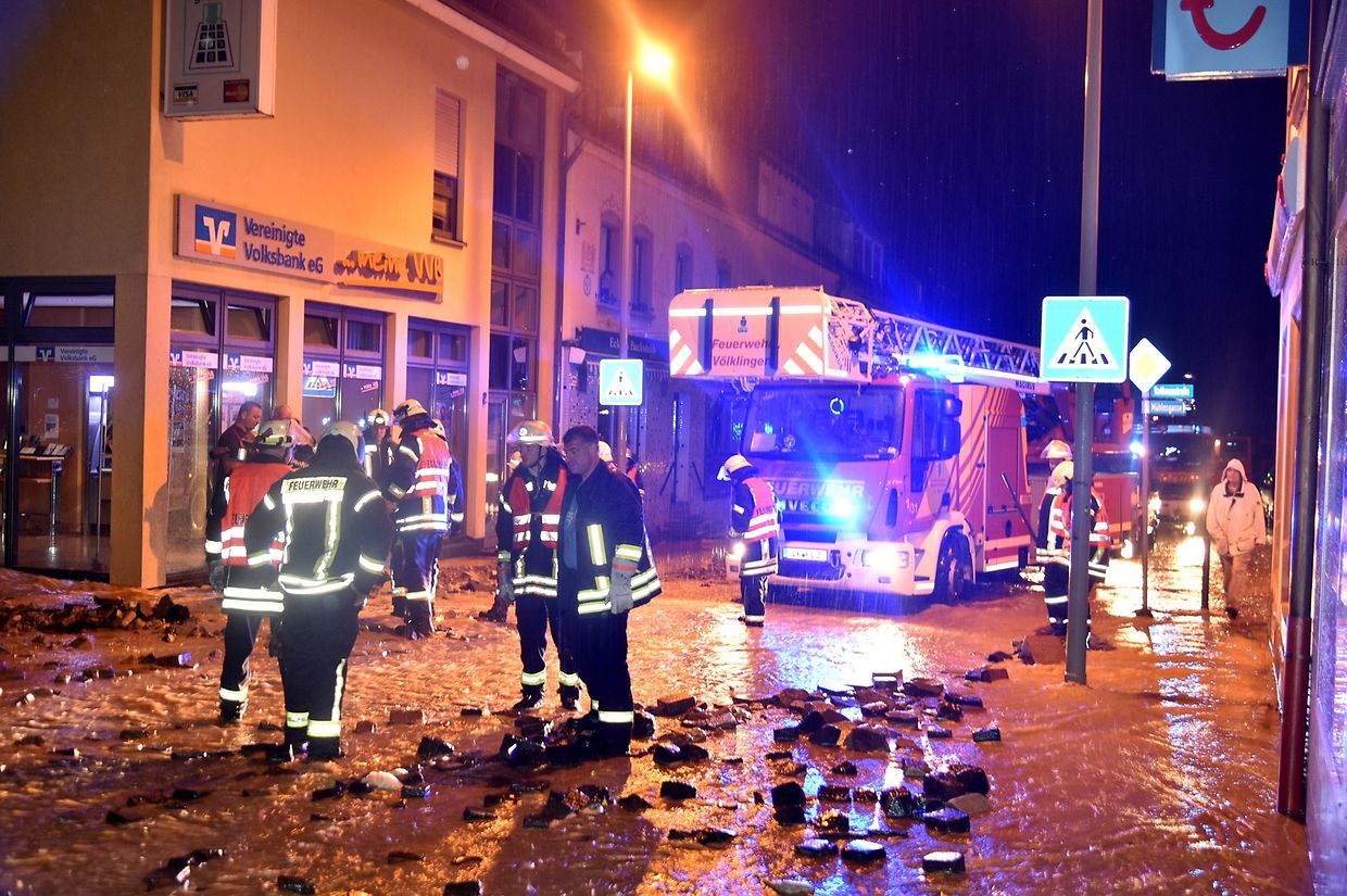 Feuerwehrleute sind auf überfluteten Straßen im Saarland im Einsatz. 