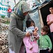 Uma mulher coloca uma máscara numa criança, num campo de refugiados na ilha grega de Lesbos.