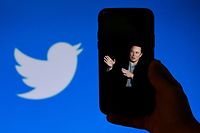 (FILES) In this file photo taken on October 4, 2022, a phone screen displays a photo of Elon Musk with the Twitter logo shown in the background, in Washington, DC. - Twitter said it will start laying off employees on November 4, 2022, as the new billionaire owner Elon Musk moves quickly after his big takeover to make the messaging platform financially sound. (Photo by OLIVIER DOULIERY / AFP)
