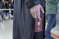 Homem russo aguarda com o passaporte alemão na fronteira com a Finlândia. 