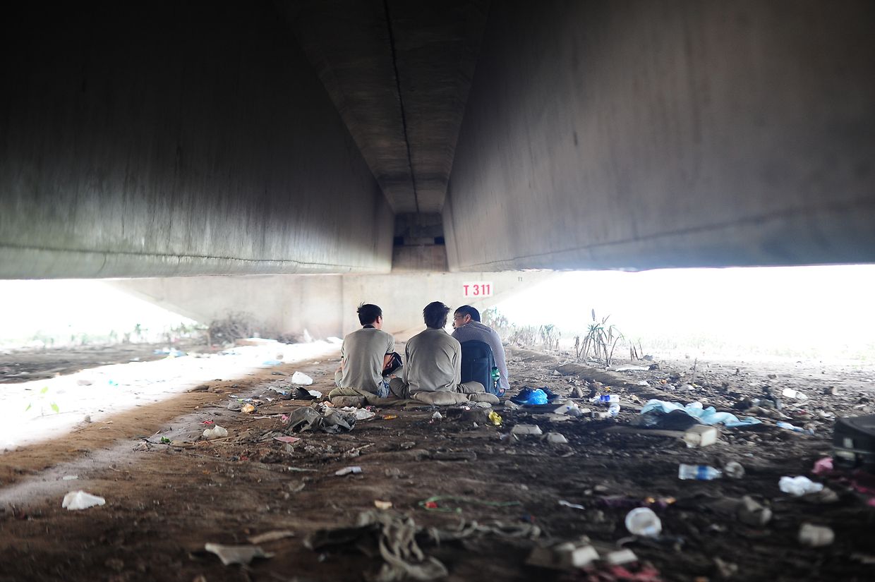 Einer der Mitarbeiter der Blue Dragon Children's Foundation spricht mit Straßenkindern unter einer Betonbrücke. 