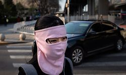 A woman wearing a face mask amid the COVID-19 coronavirus outbreak walks outside office buildings in Beijing on April 1, 2020. (Photo by NICOLAS ASFOURI / AFP)