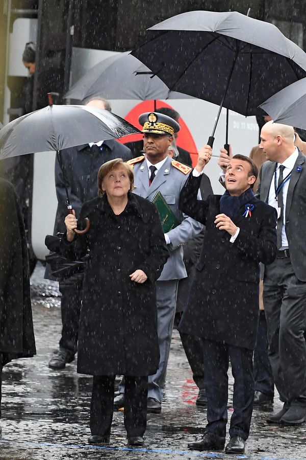 French President Emmanuel Macron (R) and German Chancellor Angela Merkel leave the Elysee Palace in Paris on November 11, 2018 for the Arc de Triomphe prior to the start of commemorations marking the 100th anniversary of the 11 November 1918 armistice, ending World War I. (Photo by Eric FEFERBERG / AFP)