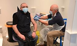 A vaccinator (R) administers an injection of AstraZeneca/Oxford Covid-19 vaccine to a patient at the vaccination centre set up at Chester Racecourse, in Chester, northwest England, on February 15, 2021. - Prime Minister Boris Johnson on February 14 called Britain hitting a target of inoculating 15 million of the most vulnerable people with a first coronavirus jab "a significant milestone", as the country prepared for the next phase of its vaccination programme. (Photo by Oli SCARFF / AFP)