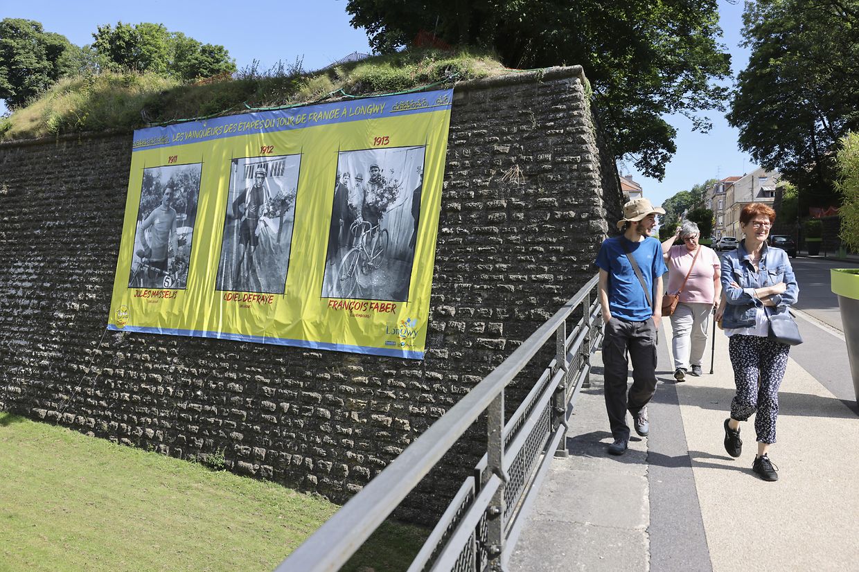 Sur les remparts à l'entrée de l'enceinte fortifiée de Longwy, les photos des anciens vainqueurs d'étape sont affichées en grand.