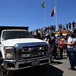 People cheer as trucks with humanitarian aid to Venezuela approach the Brazil-Venezuela border in Pacaraima, Roraima state, Brazil on February 23, 2019. - Venezuela braced for a showdown between the military and regime opponents at the Colombian border on Saturday, when self-declared acting president Juan Guaido has vowed humanitarian aid would enter his country despite a blockade. Early Saturday two large trucks -driven by Venezuelans and escorted by Brazilian police- carrying eight tonnes of emergency aid left Boa Vista in Brazil en route to the Venezuelan border. (Photo by Nelson Almeida / AFP)