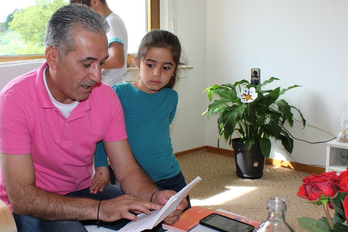 Nazir tente de lire et comprendre le texte reçu par l'école de sa fille, non sans difficulté.