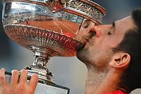 Serbia's Novak Djokovic kisses The Mousquetaires Cup (The Musketeers) after winning against Greece's Stefanos Tsitsipas at the end of their men's final tennis match on Day 15 of The Roland Garros 2021 French Open tennis tournament in Paris on June 13, 2021. (Photo by Anne-Christine POUJOULAT / AFP)