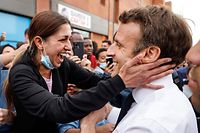 TOPSHOT - French incumbent president and candidate of La Republique en Marche (LREM) party for the presidential election Emmanuel Macron (R) greets an inhabitant during a campaign visit in the "Fontaine d'Ouche" neighborhood in Dijon, on March 28, 2022. (Photo by Ludovic MARIN / AFP)