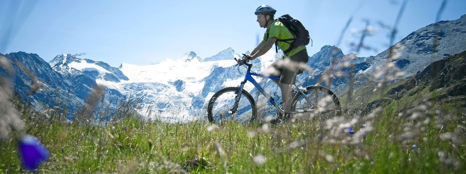 Vor dem Hintergrund des Moirygletschers und des Grand Cornier (3 845 Meter) erkundet ein Biker die  Alpweiden oberhalb des Moiry-Stausees im Kanton Wallis.