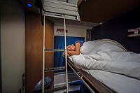 female traveler in sleeper cabin of train at night. conceptual shot for eco-friendly woman traveling.